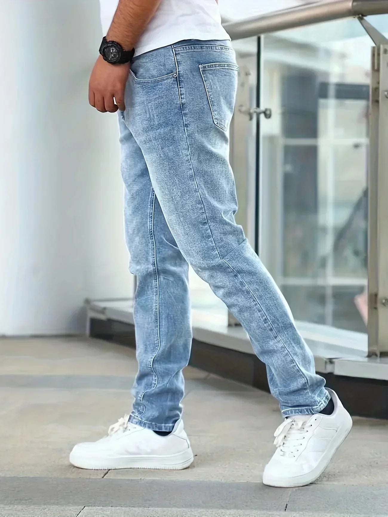 Person wearing light blue jeans and white sneakers in an urban setting