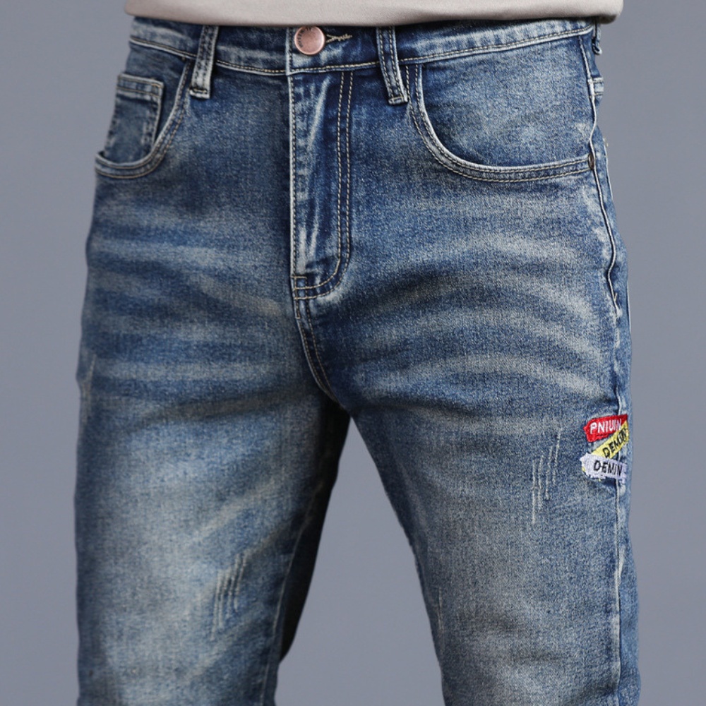 Blue jeans with patches on a gray background