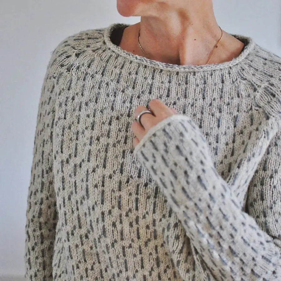 Person wearing a patterned sweater with a neutral background