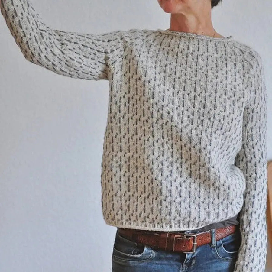 Person wearing a textured sweater and jeans against a plain background