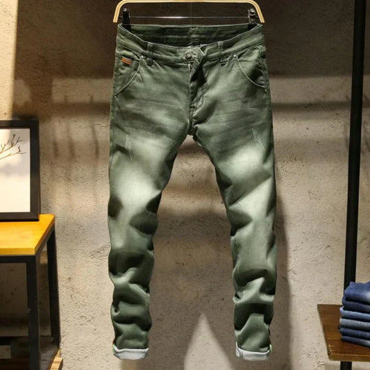 Green jeans hanging on a rack against a textured wall.