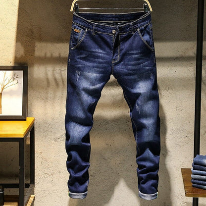 Blue jeans on a hanger against a textured wall.