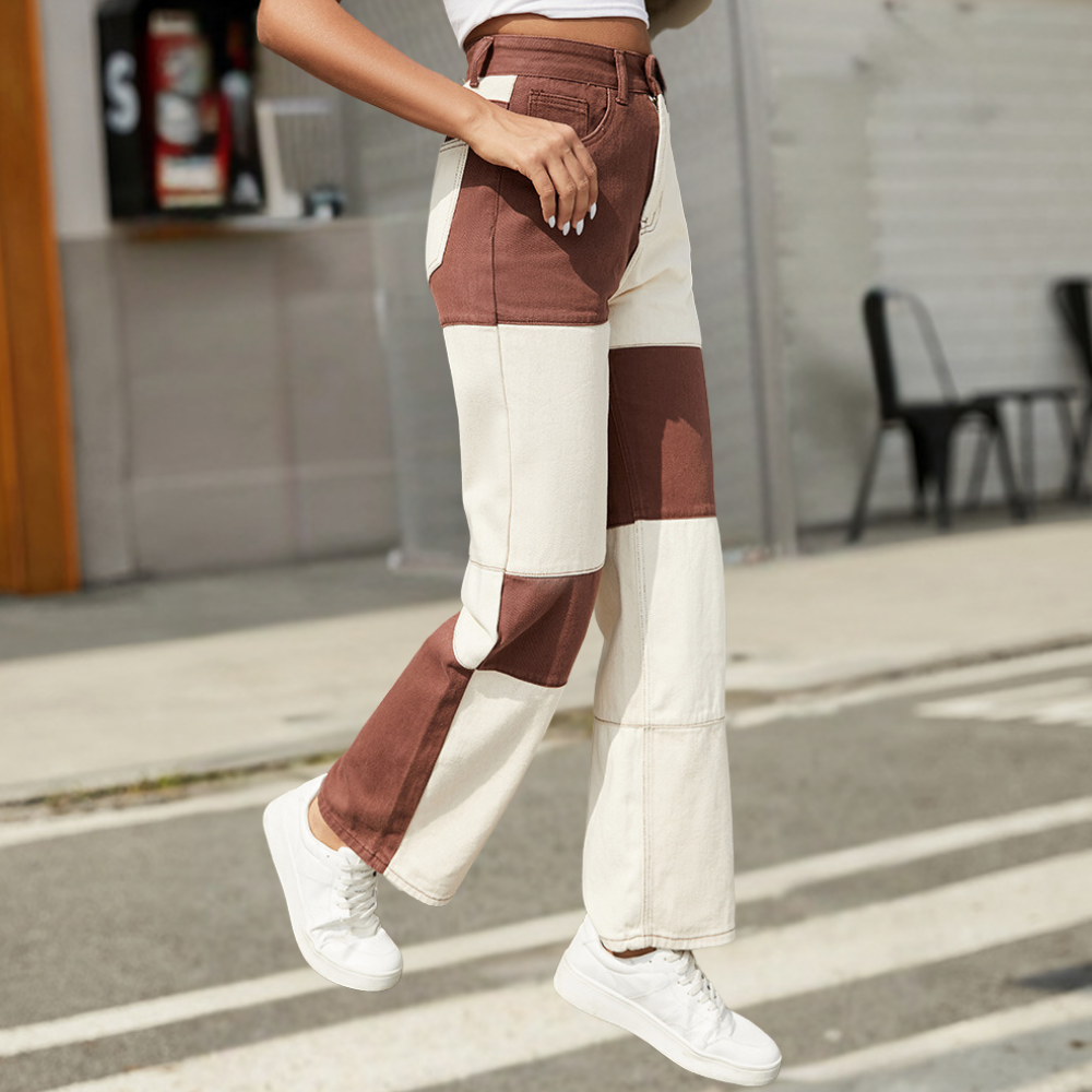 Person wearing brown and white pants with white sneakers on a street.