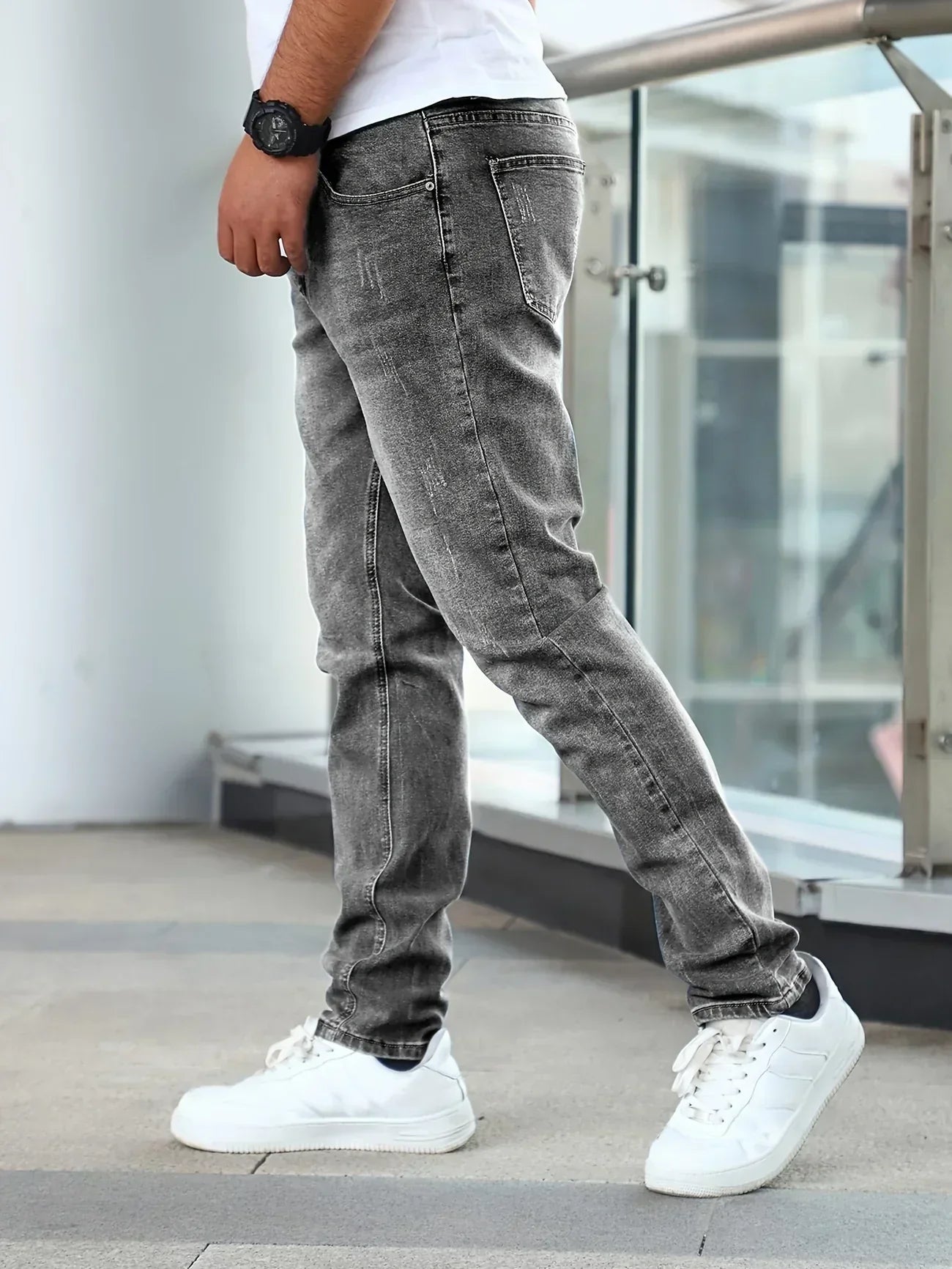 Person wearing gray jeans and white sneakers in an urban setting
