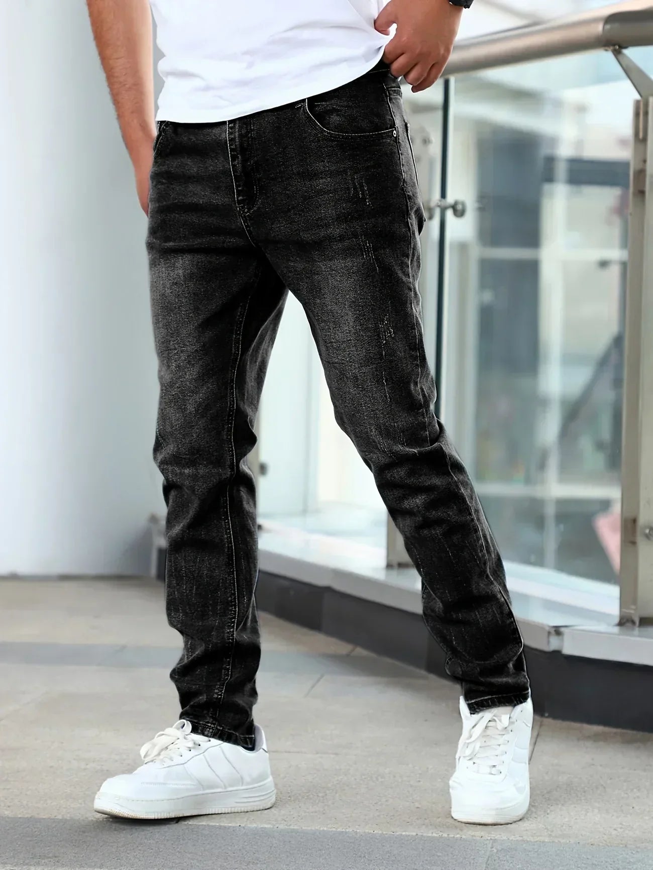 Person wearing black jeans and white sneakers in an urban setting