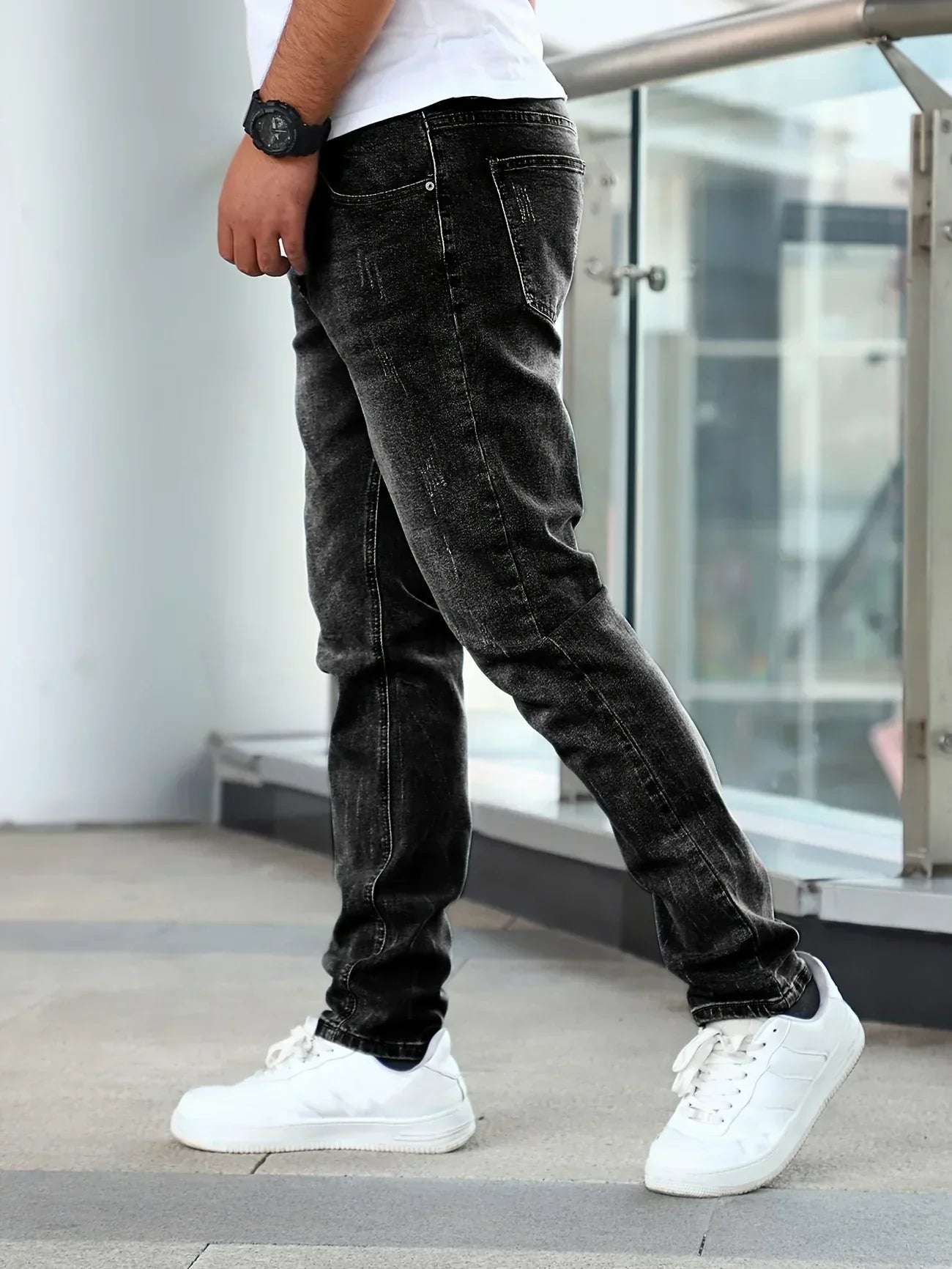 Person wearing black jeans and white sneakers in an urban setting