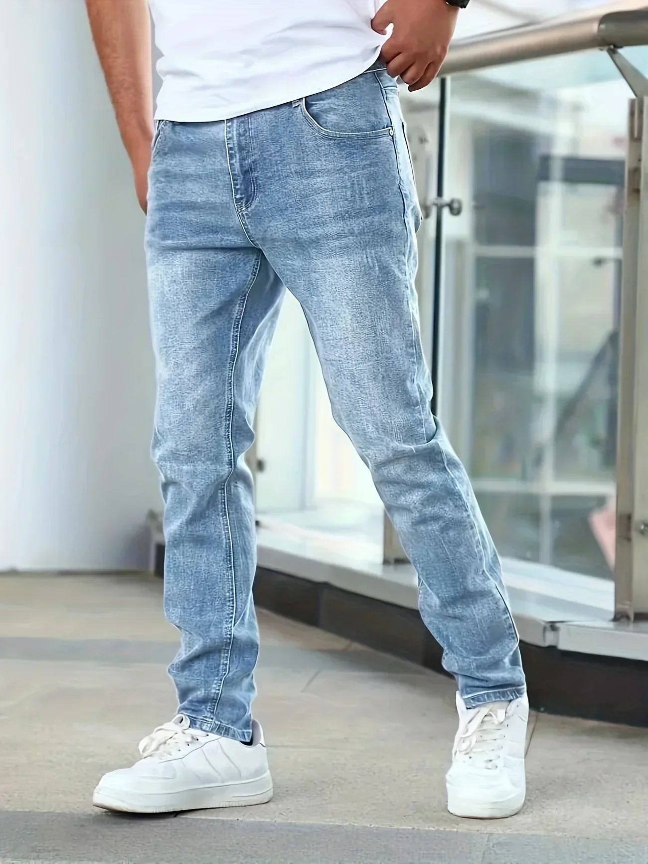 Person wearing light blue jeans and white sneakers in an indoor setting