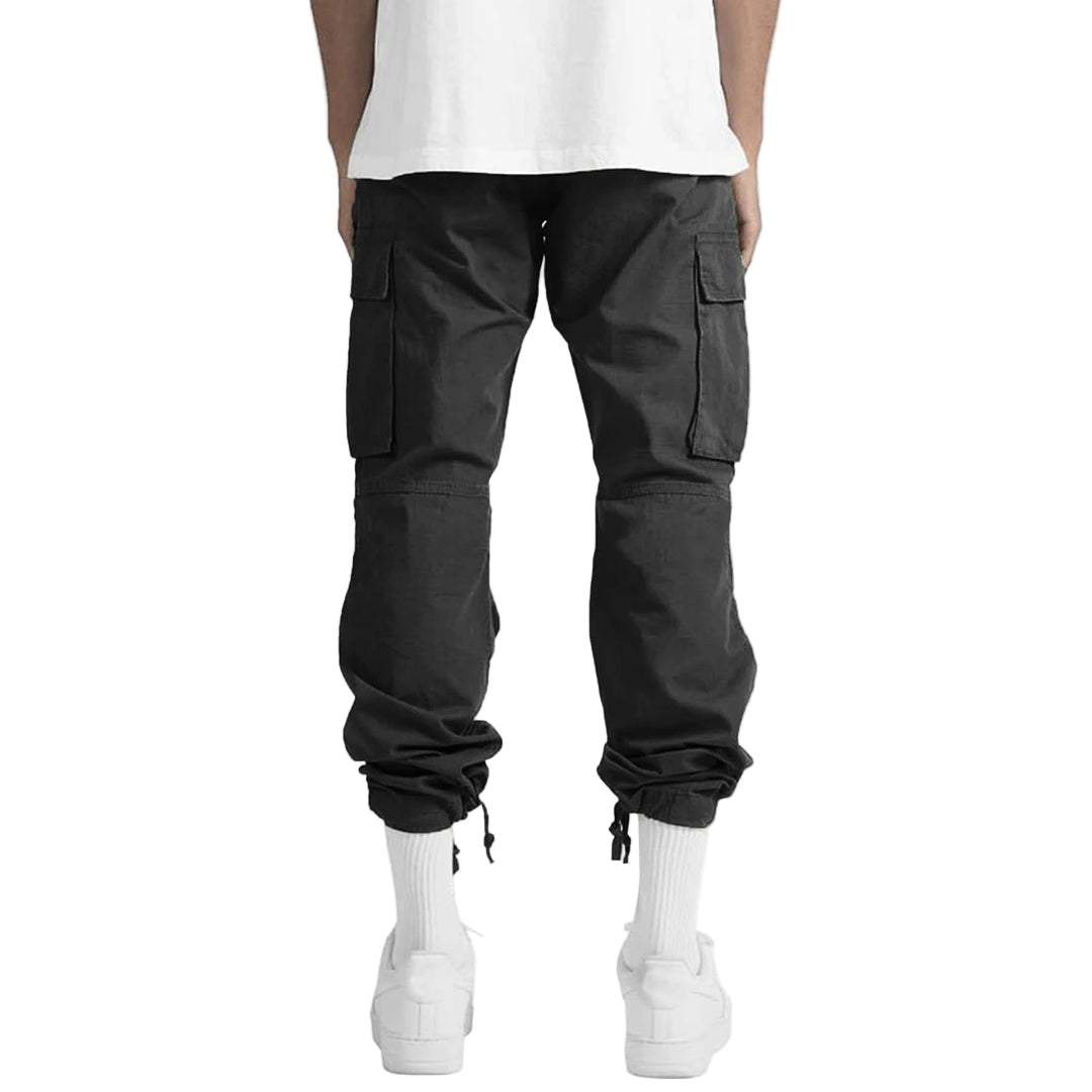 Person wearing black cargo pants and white shoes on a plain background