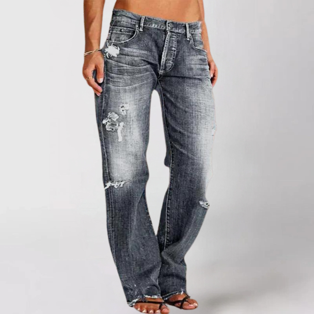 Distressed denim jeans on a plain background