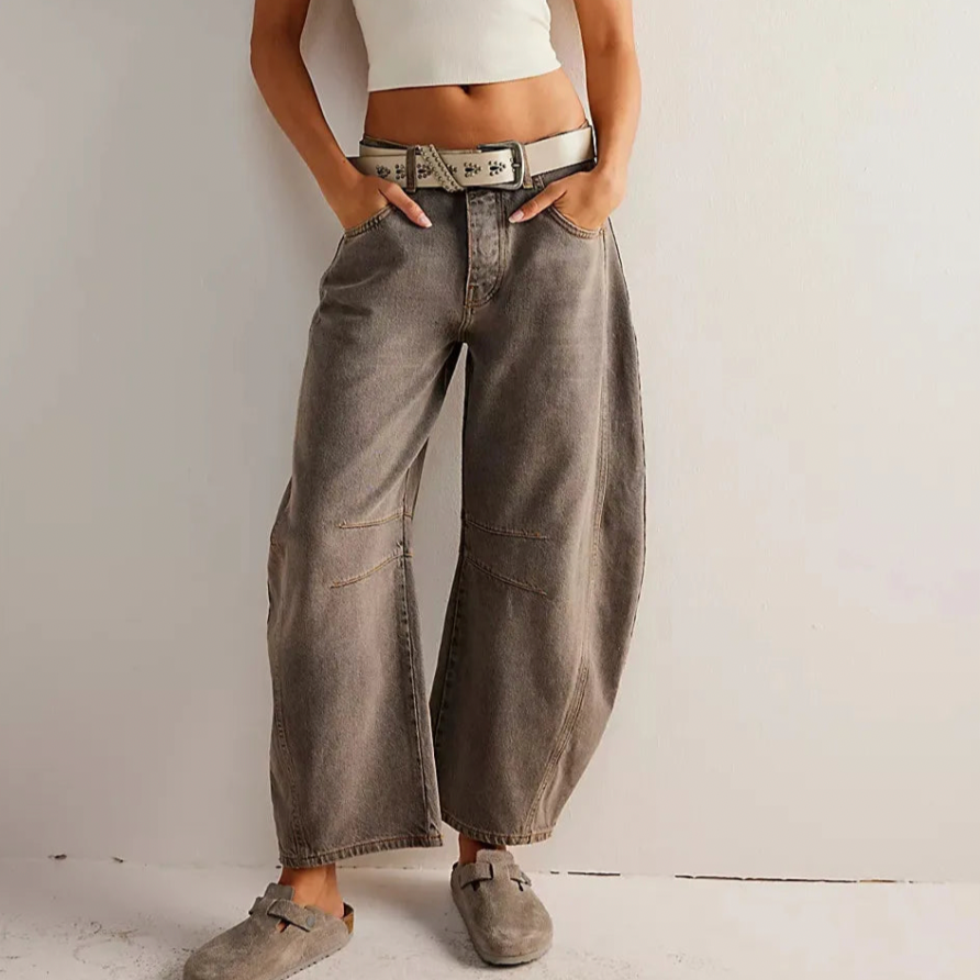 Person wearing wide-leg jeans and a white top against a plain background