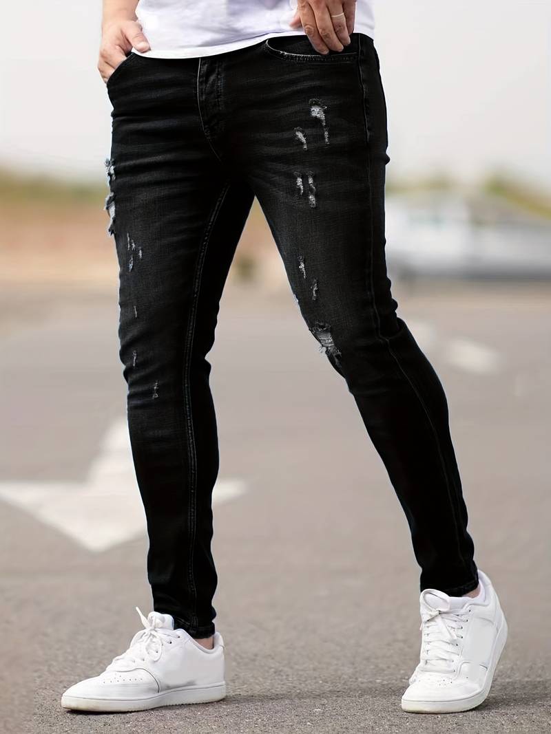 Person wearing black distressed jeans and white sneakers on a blurred background