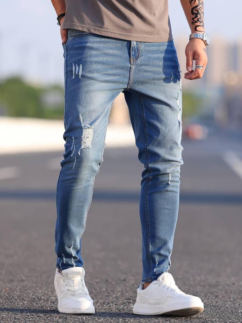 Person wearing light blue distressed jeans and white sneakers on a blurred street background