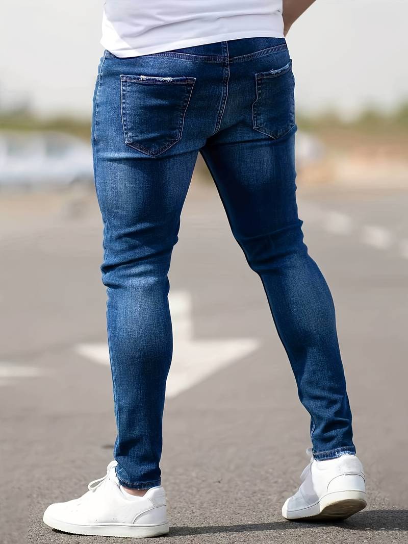 Person wearing blue jeans and white sneakers on a road.
