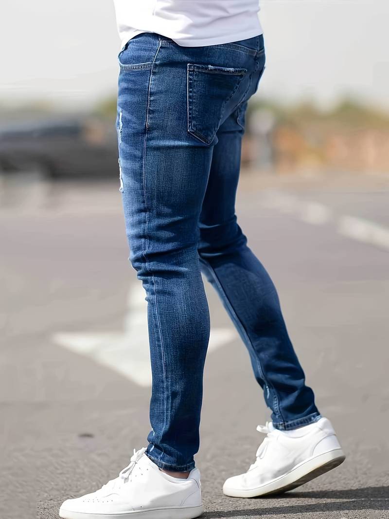 Person wearing blue jeans and white sneakers on a blurred street background