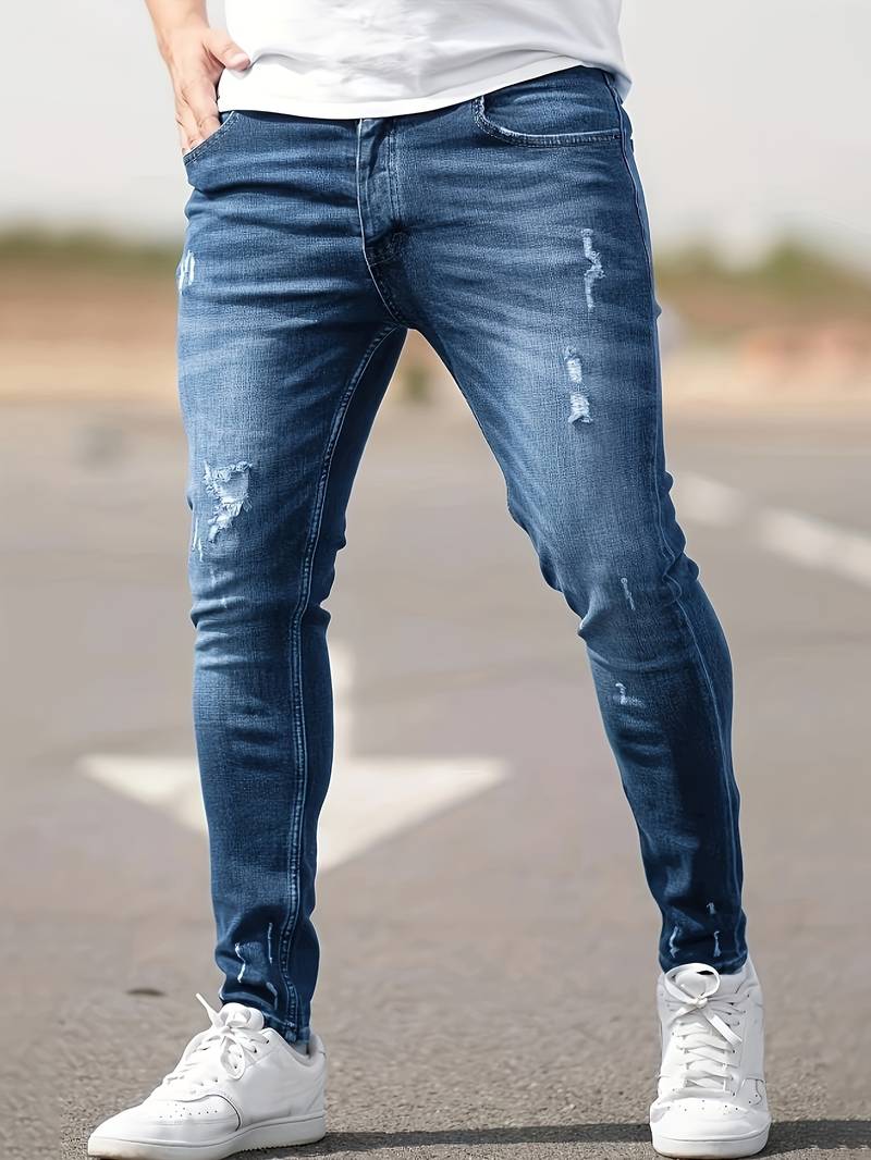 Person wearing blue distressed jeans and white sneakers on a blurred background