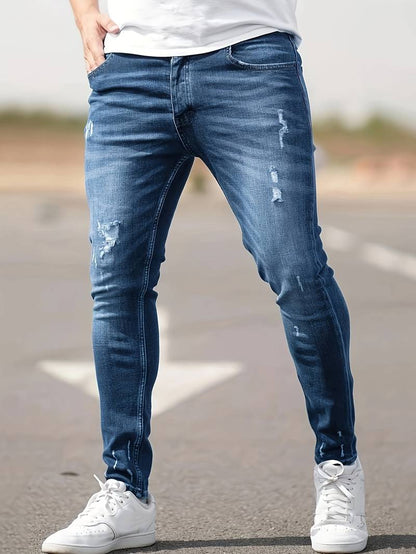 Person wearing blue distressed jeans and white sneakers on a blurred background