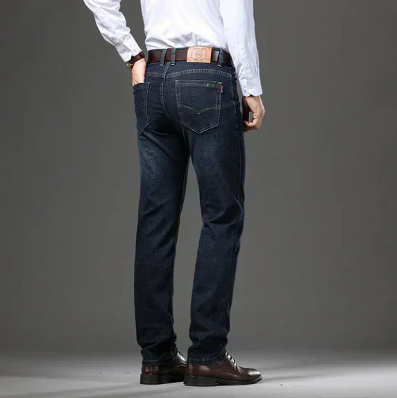 Person wearing dark blue jeans and a white shirt on a gray background