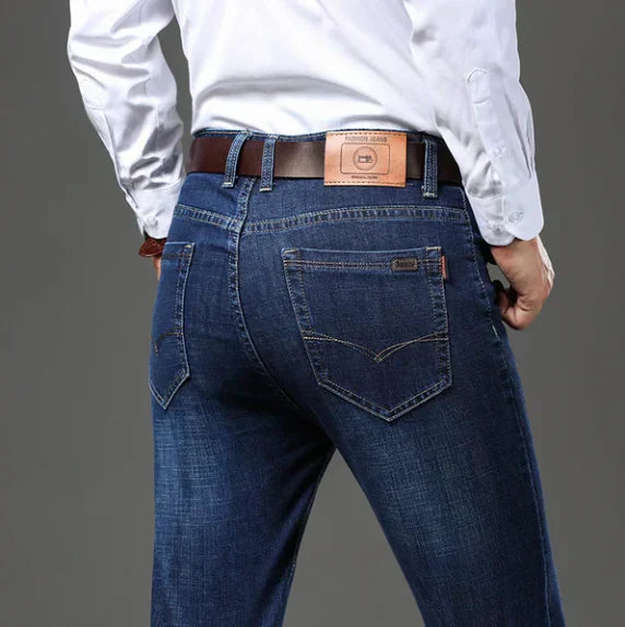 Person wearing blue jeans and a white shirt with a brown belt on a gray background