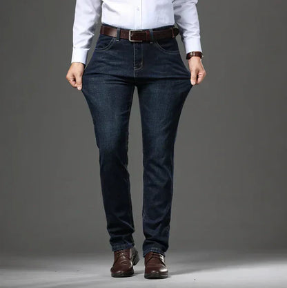 Person wearing dark blue jeans and a white shirt on a gray background