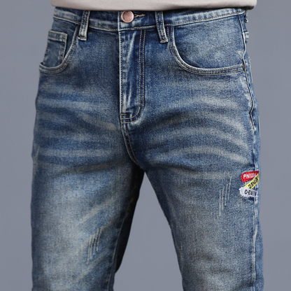 Blue jeans with patches on a gray background