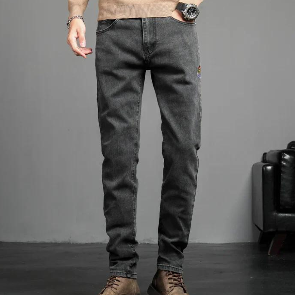 Person wearing dark gray jeans with a neutral background