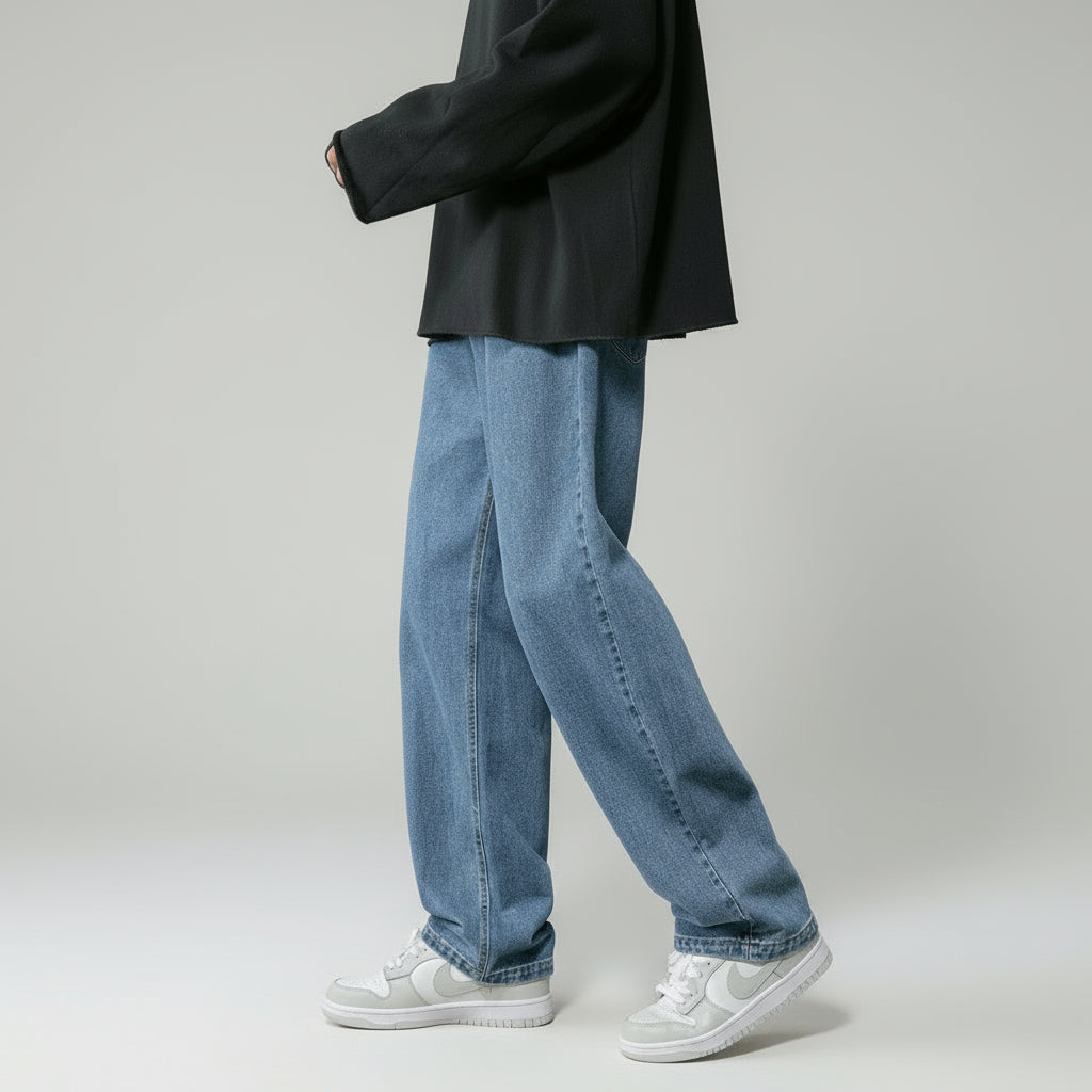 Person wearing blue jeans and white sneakers on a gray background