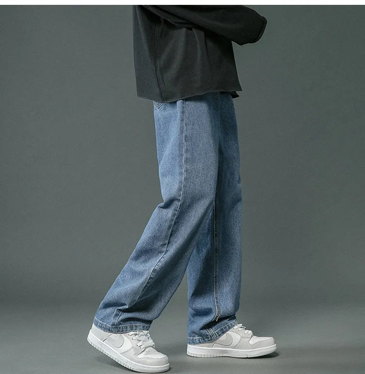 Person wearing blue jeans and white sneakers on a gray background