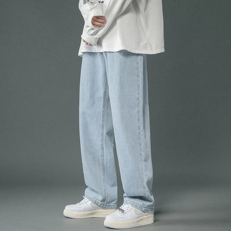 Person wearing light blue jeans and white sneakers on a gray background